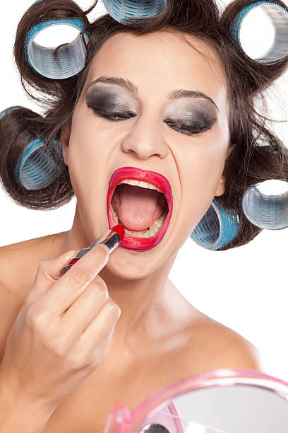 Funny woman with curlers and bad makeup applying lipstic Funny woman with curlers and bad makeup applying lipstic