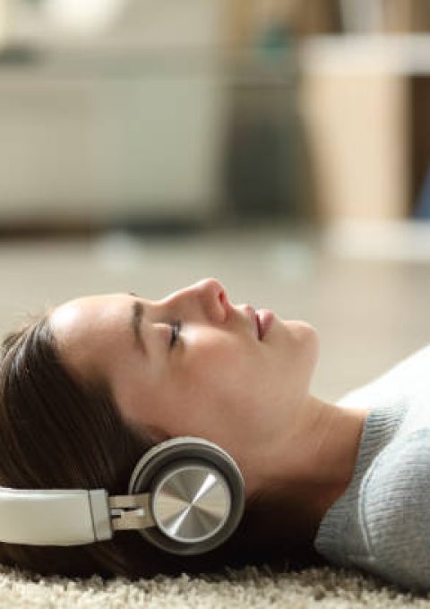 "امرأة مسترخية في السرير تستمع لأصوات هادئة لتحسين النوم العميق"